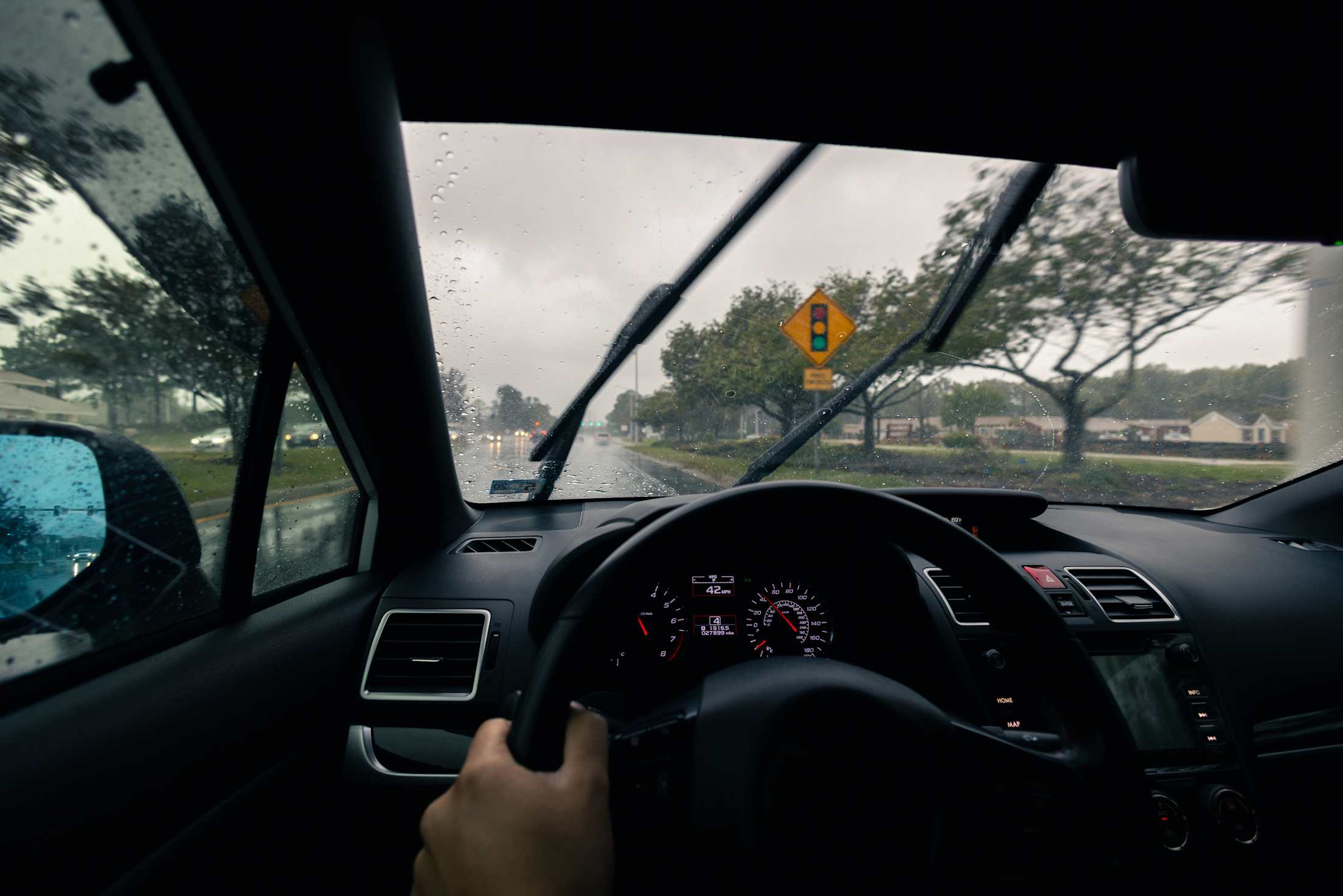 A view of a car dashboard and windshield wipers in the rain.