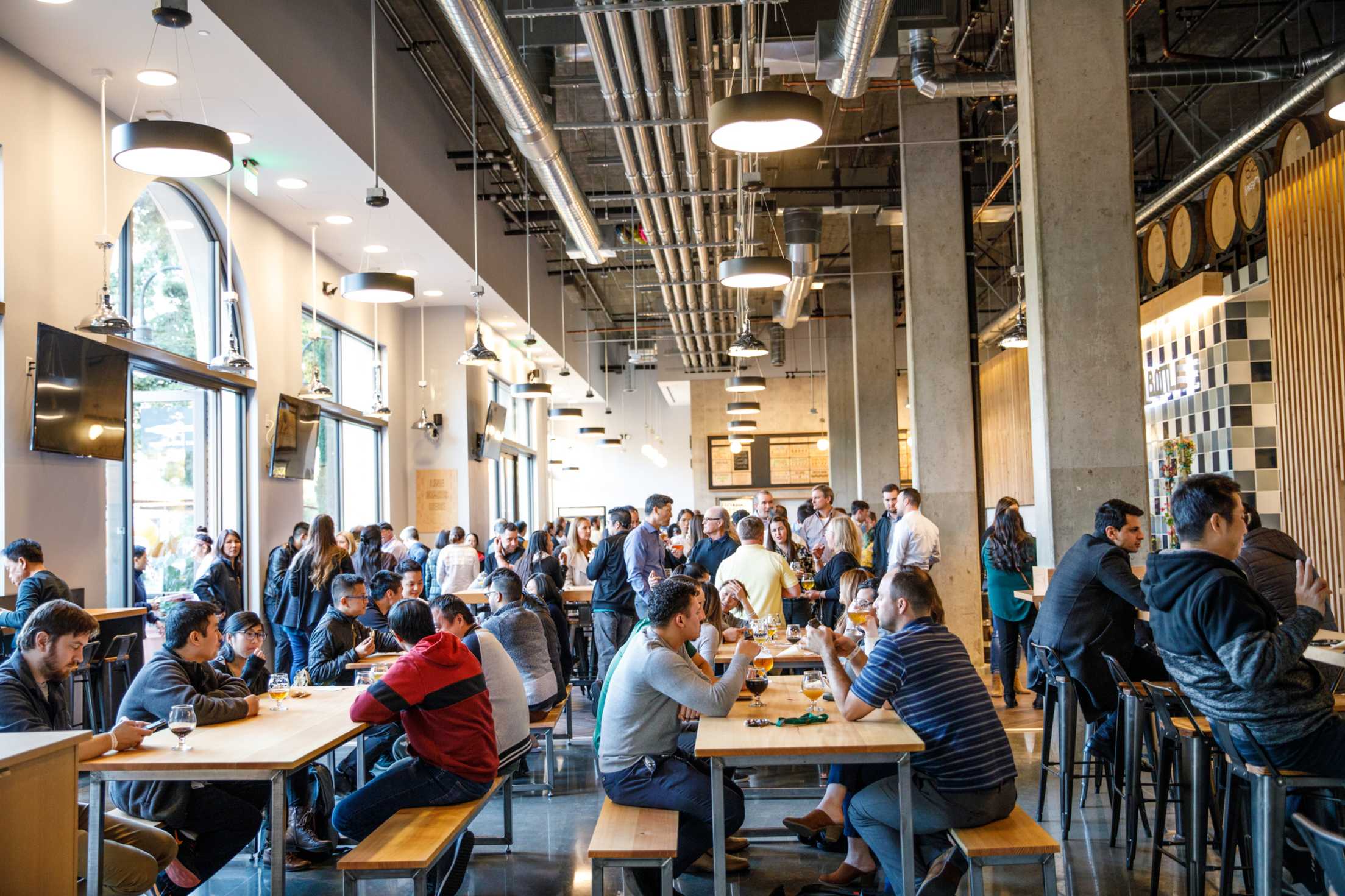 an airy brewpub filled with people at long wooden tables