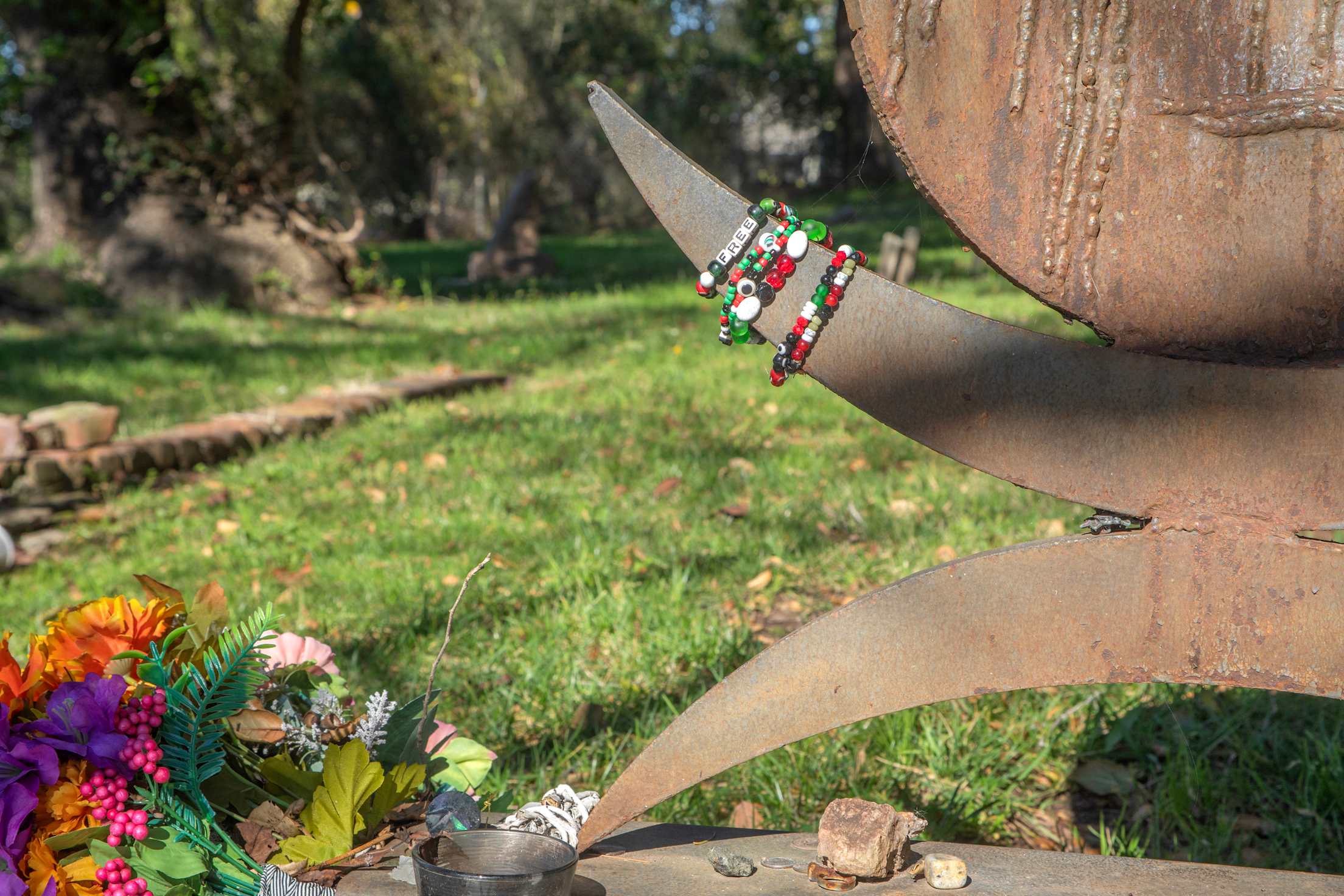 a close-up of gravestone with flowers and bracelets that read 'free'