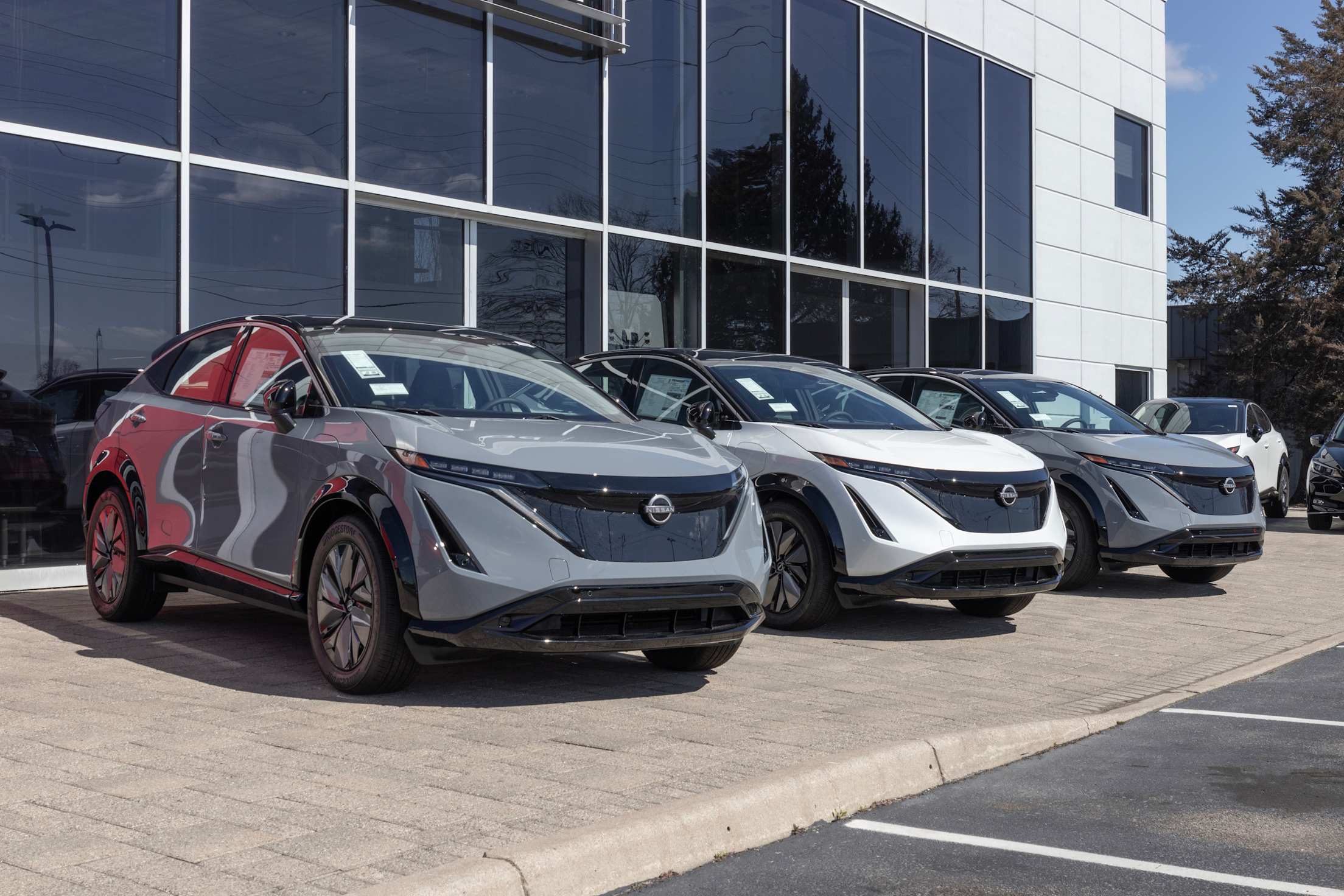 A row of Nissan Ariya EV SUVs at a dealership.