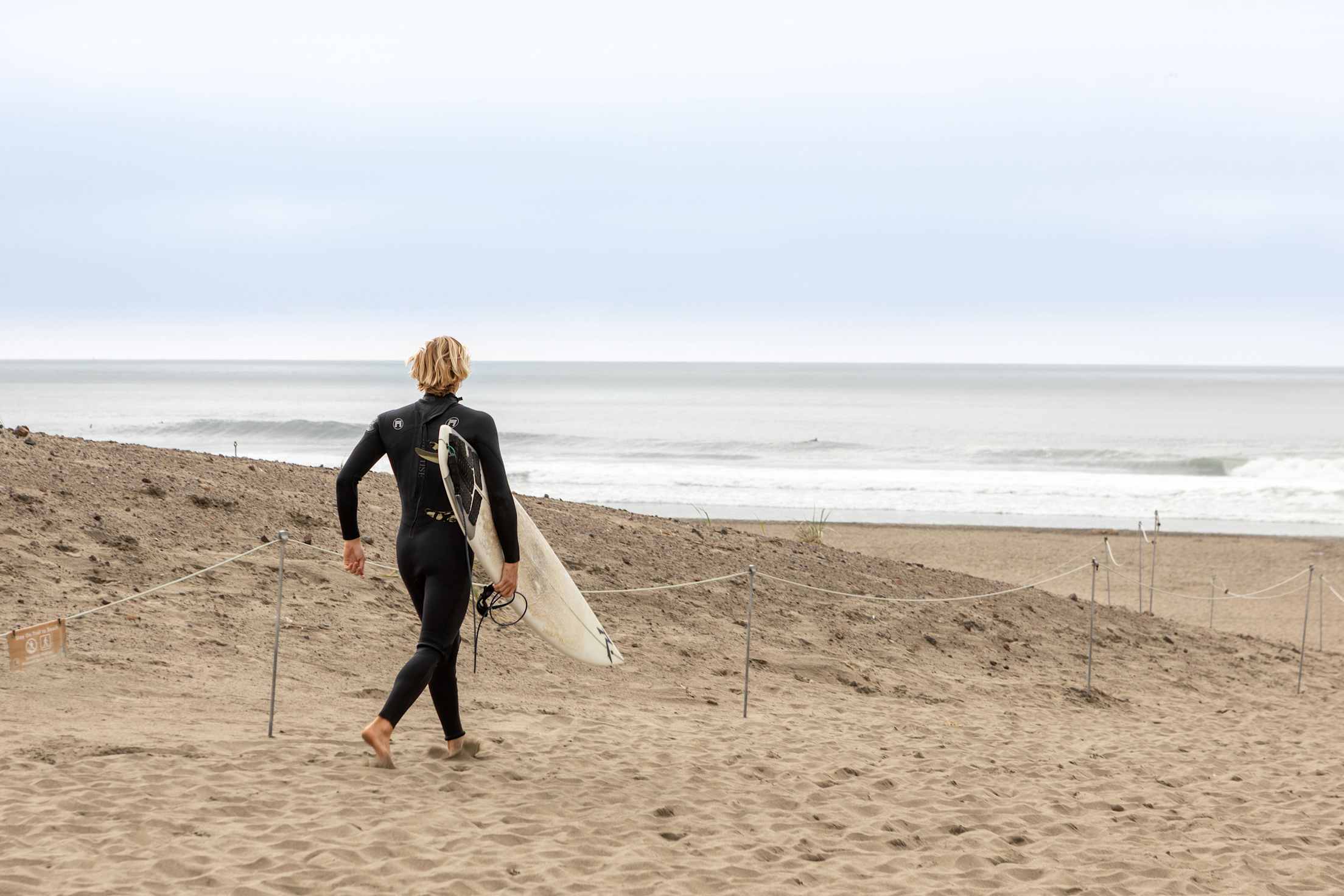 A surfer heads to Ocean Beach in the Outer Sunset District of San Francisco to catch some waves.