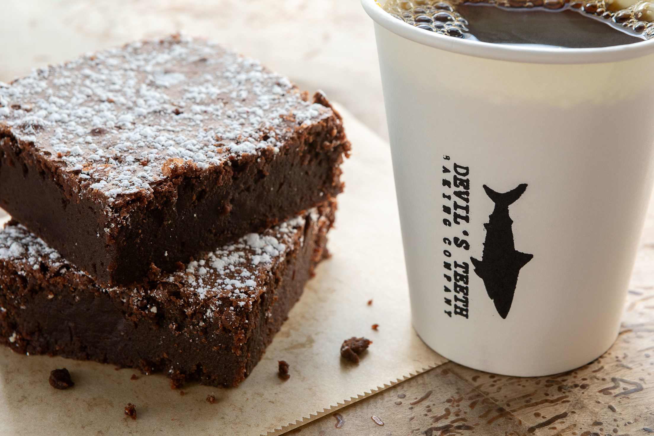 Brownies and a cup of cofee on a table outside of Devil's Teeth Baking Company.