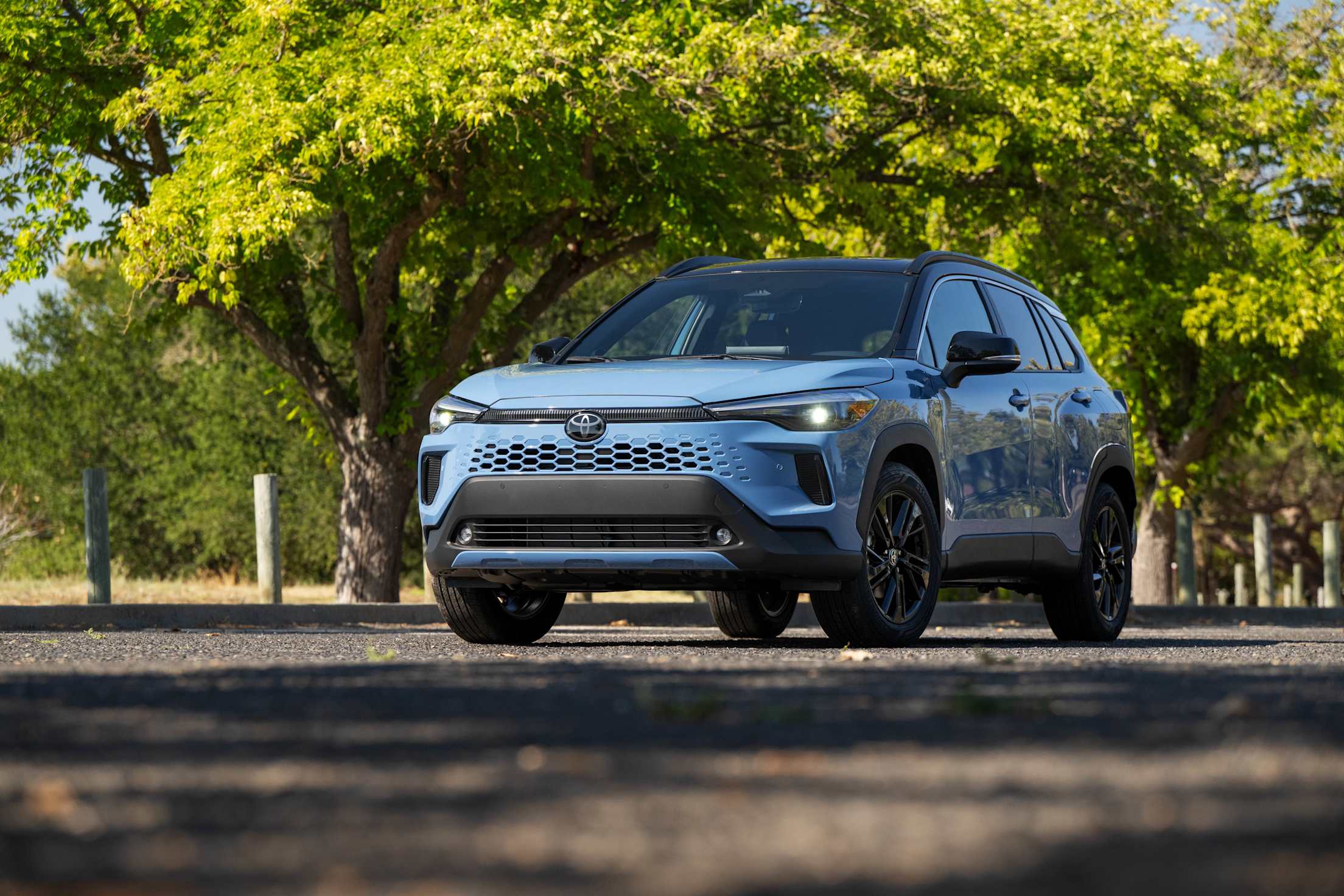 2026 Toyota Corolla Cross Hybrid XSE AWD in Cavalry Blue on a tree-lined street.