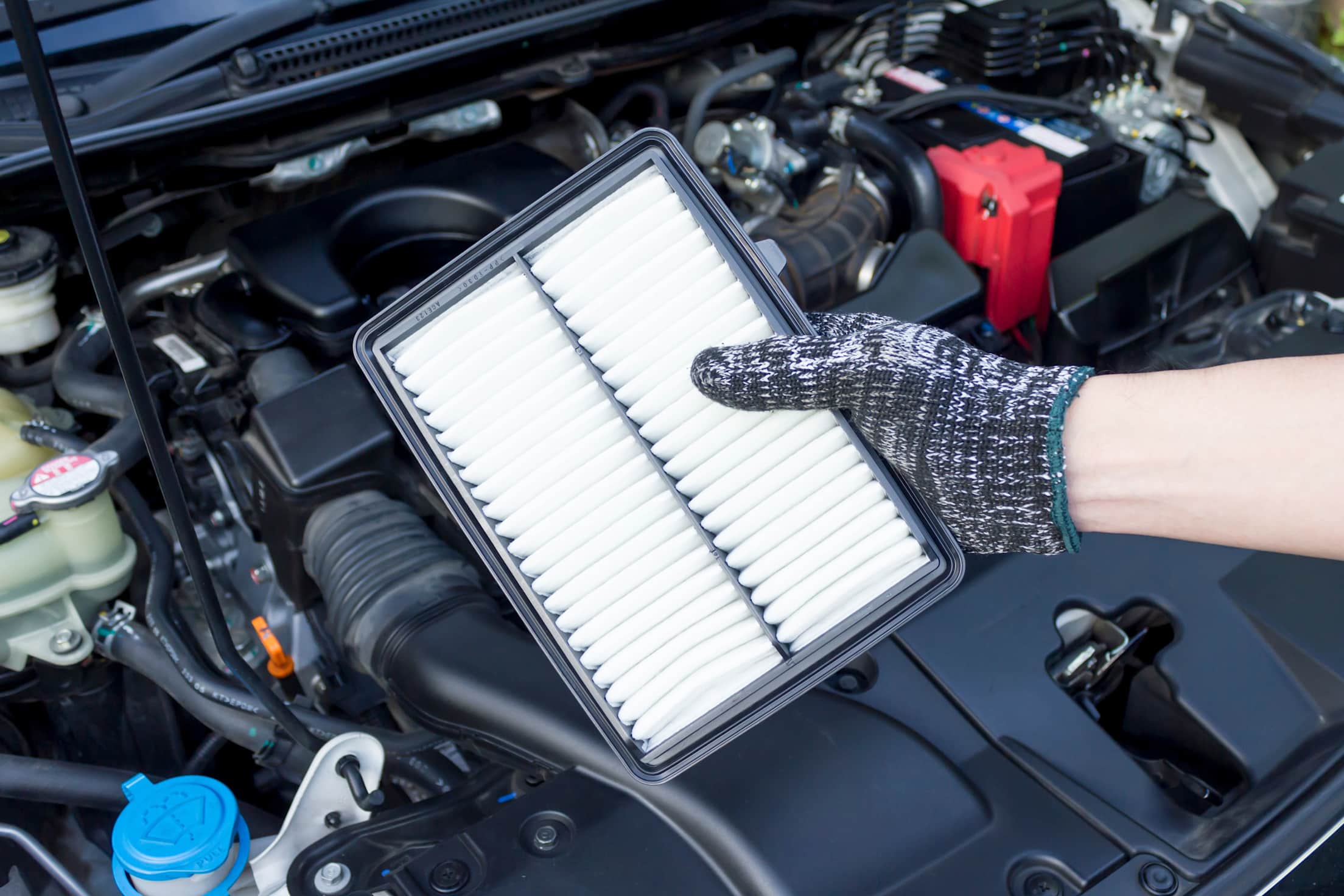 A mechanic inspects and replaces a car engine air filter.