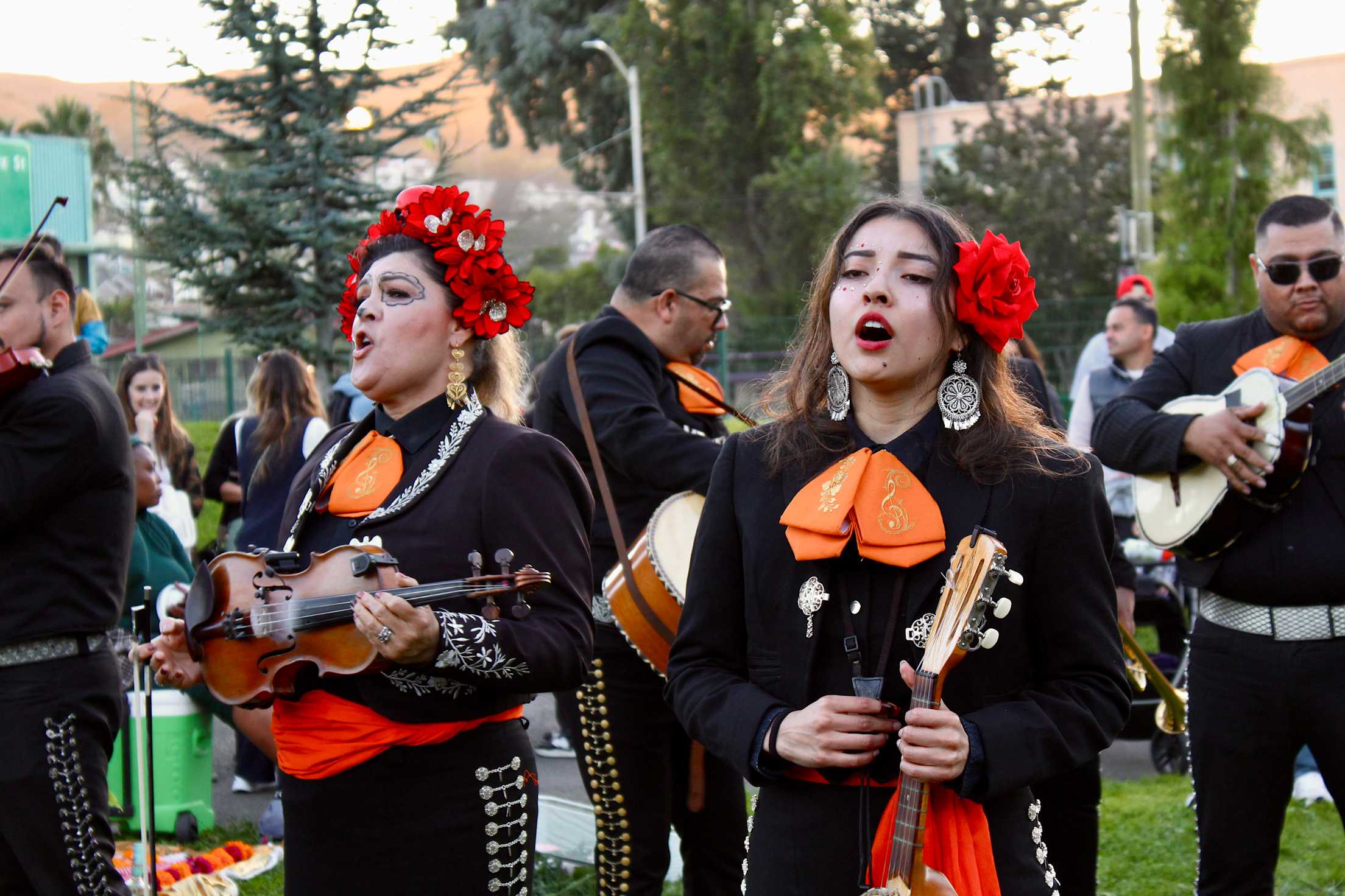mariachi singers perform outside at a park in San Francisco, wearing black and red