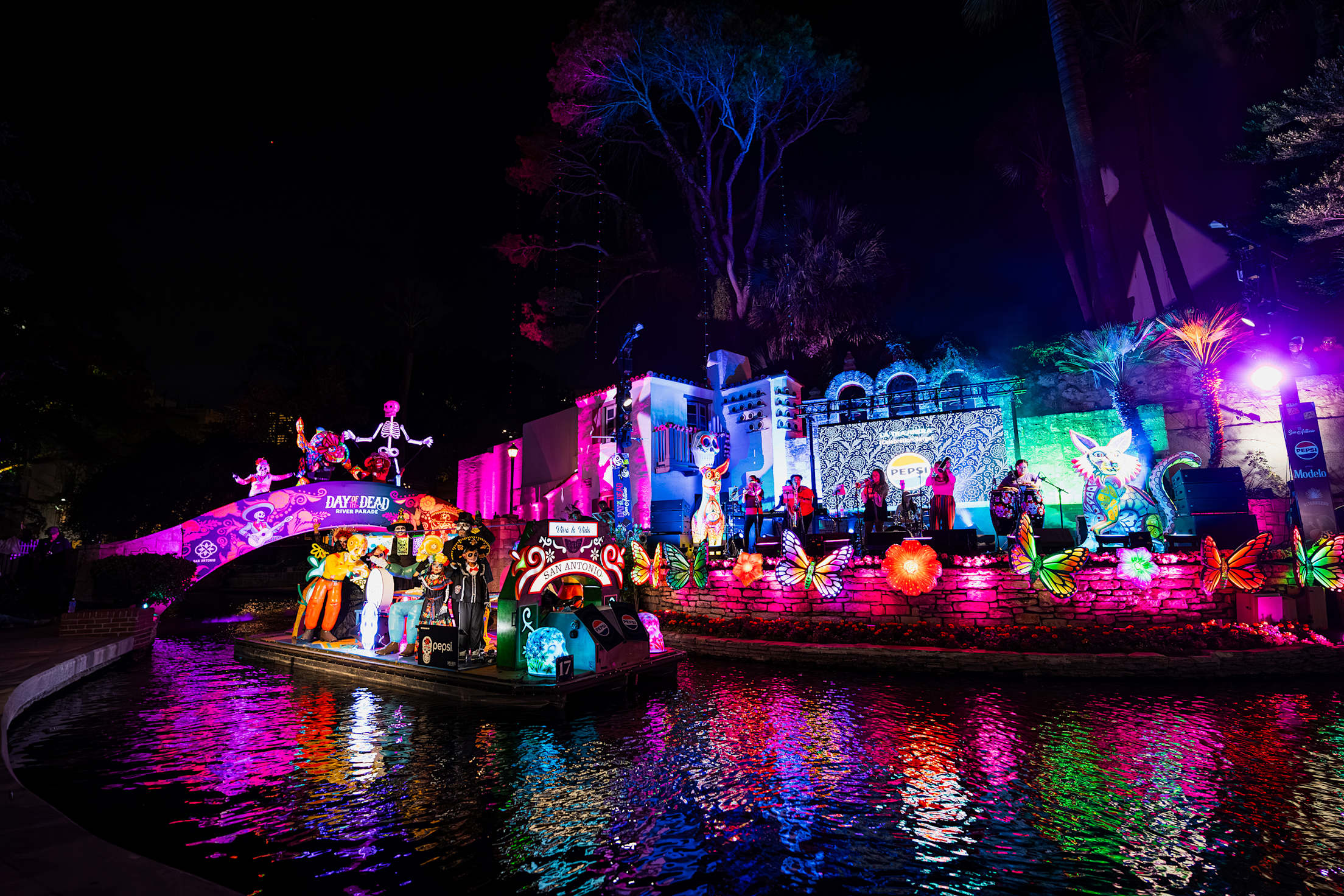 colorfully lit up boats and floats on a river at night