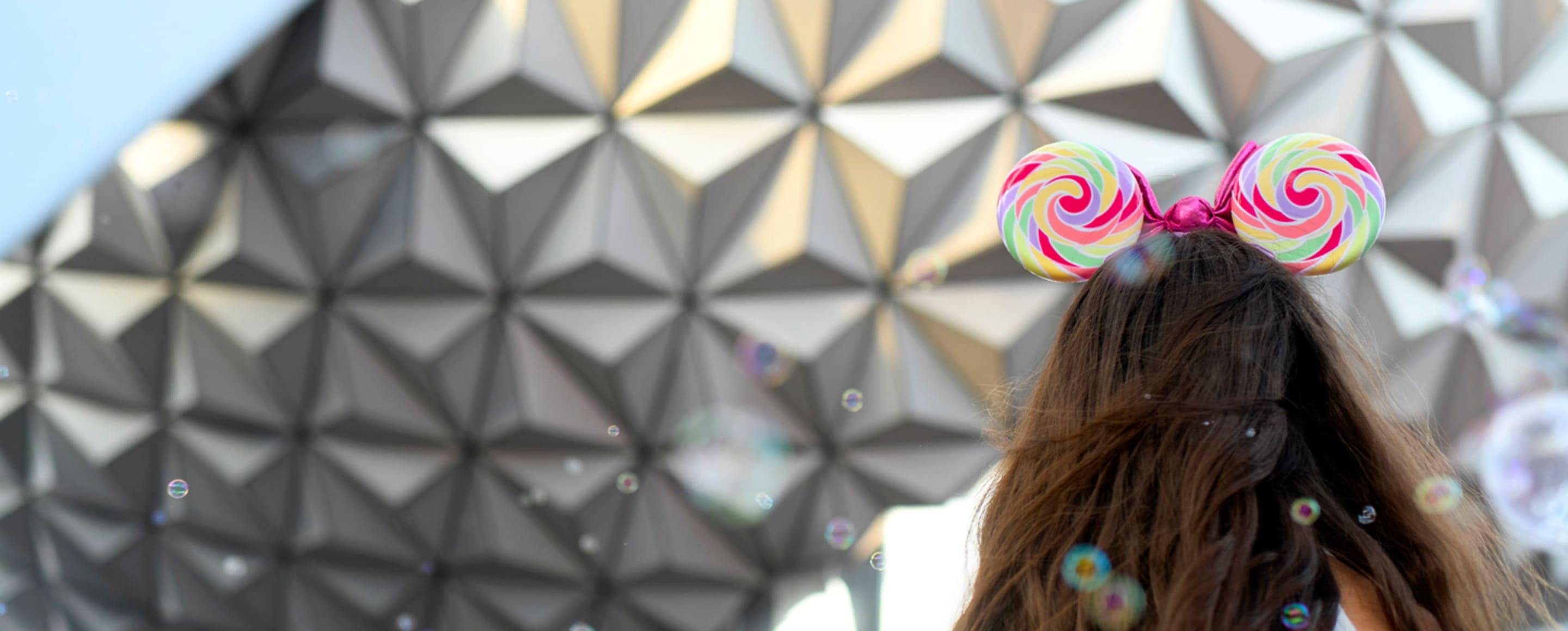girl in mickey mouse ears looking at epcot sphere at walt disney world