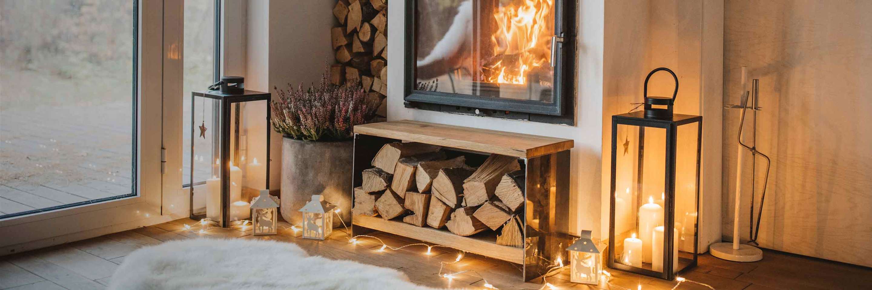 A fireplace glows with string lights and candles below.