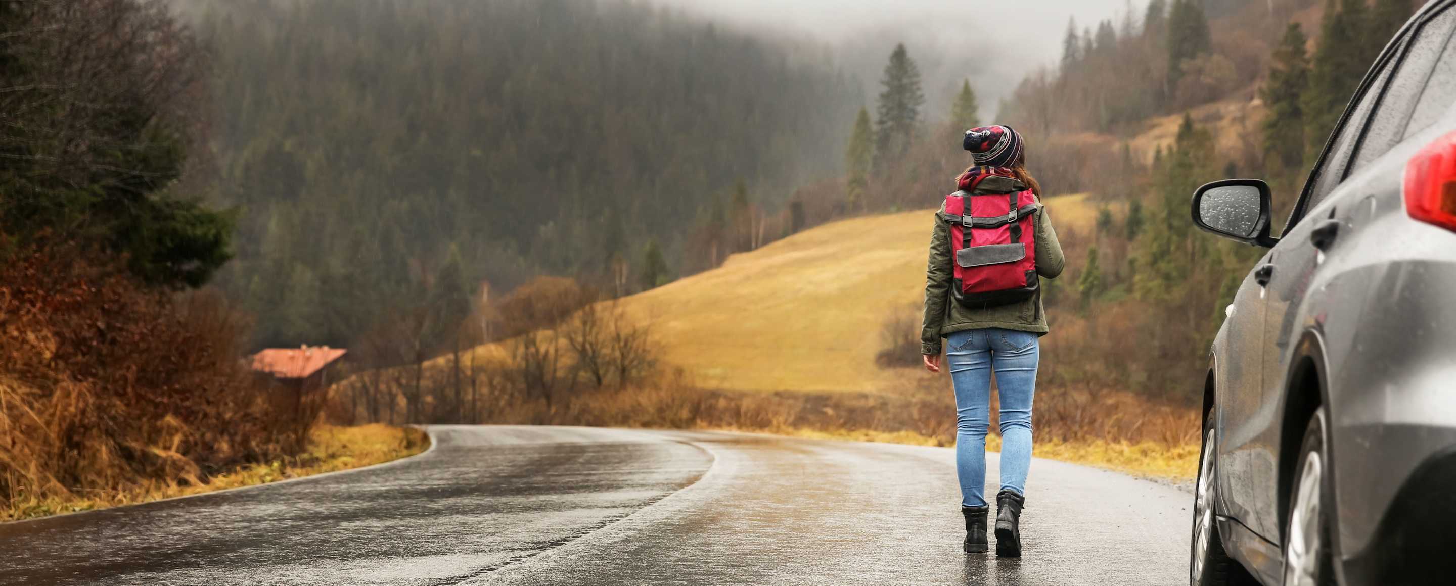 AAA Member walking away from her car on a mountain road.