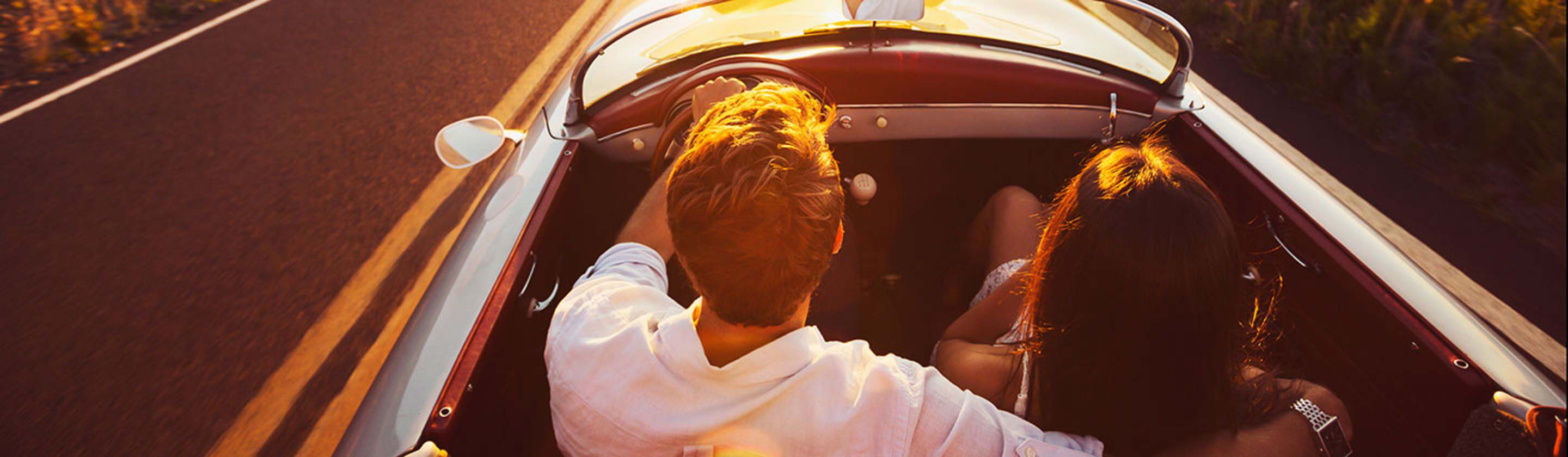A couple drives a convertible covered with AAA car insurance 