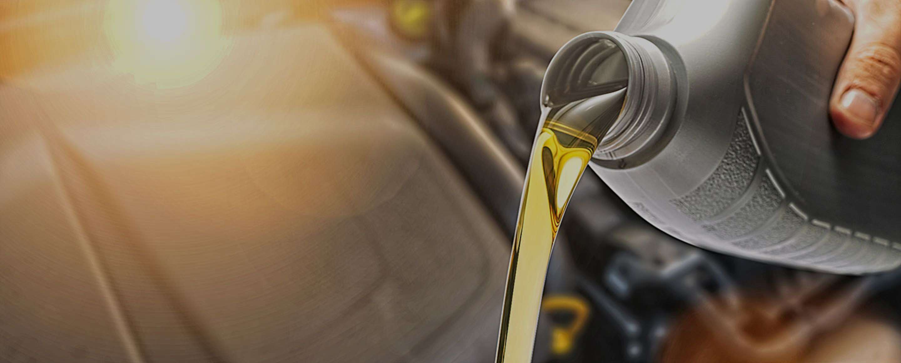 close up of a AAA mechanic pouring oil into a car at an auto repair center.