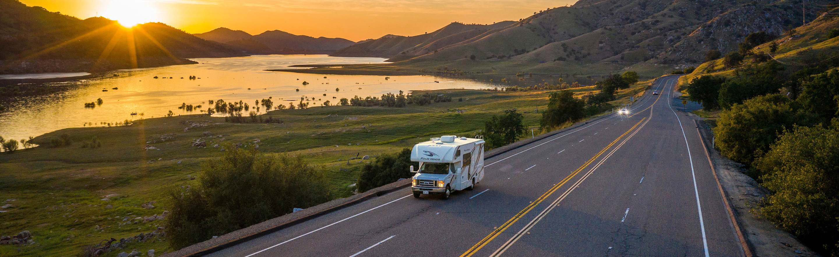 AAA Members drive an RV on the highway at sunset.