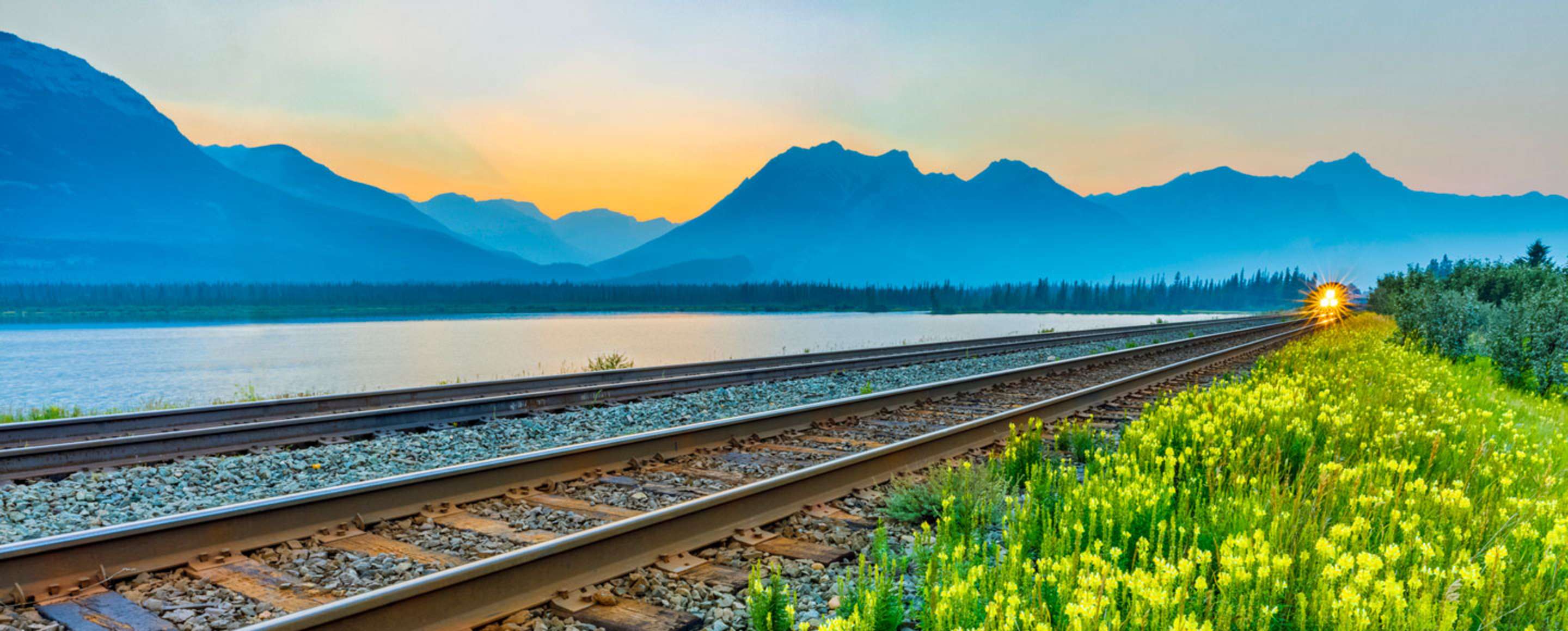 train on tracks near lake in jasper national park