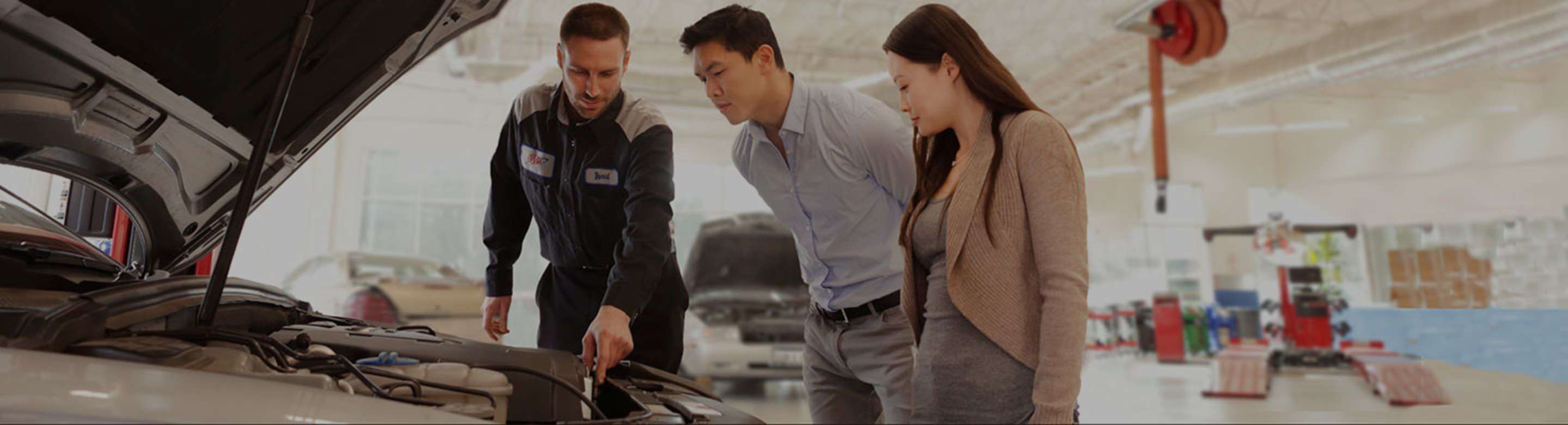 a couple looks at their car with a mechanic at AAA Car Care Plus in San Jose Brokaw Commons