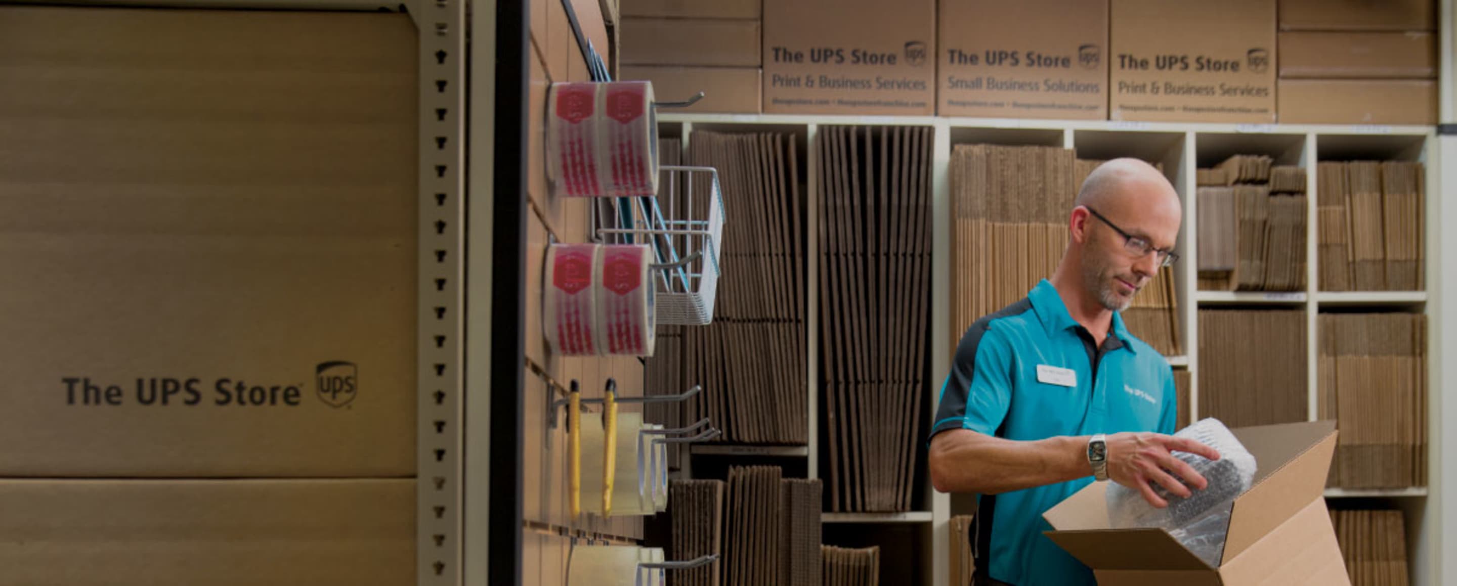 UPS store employee packing a box
