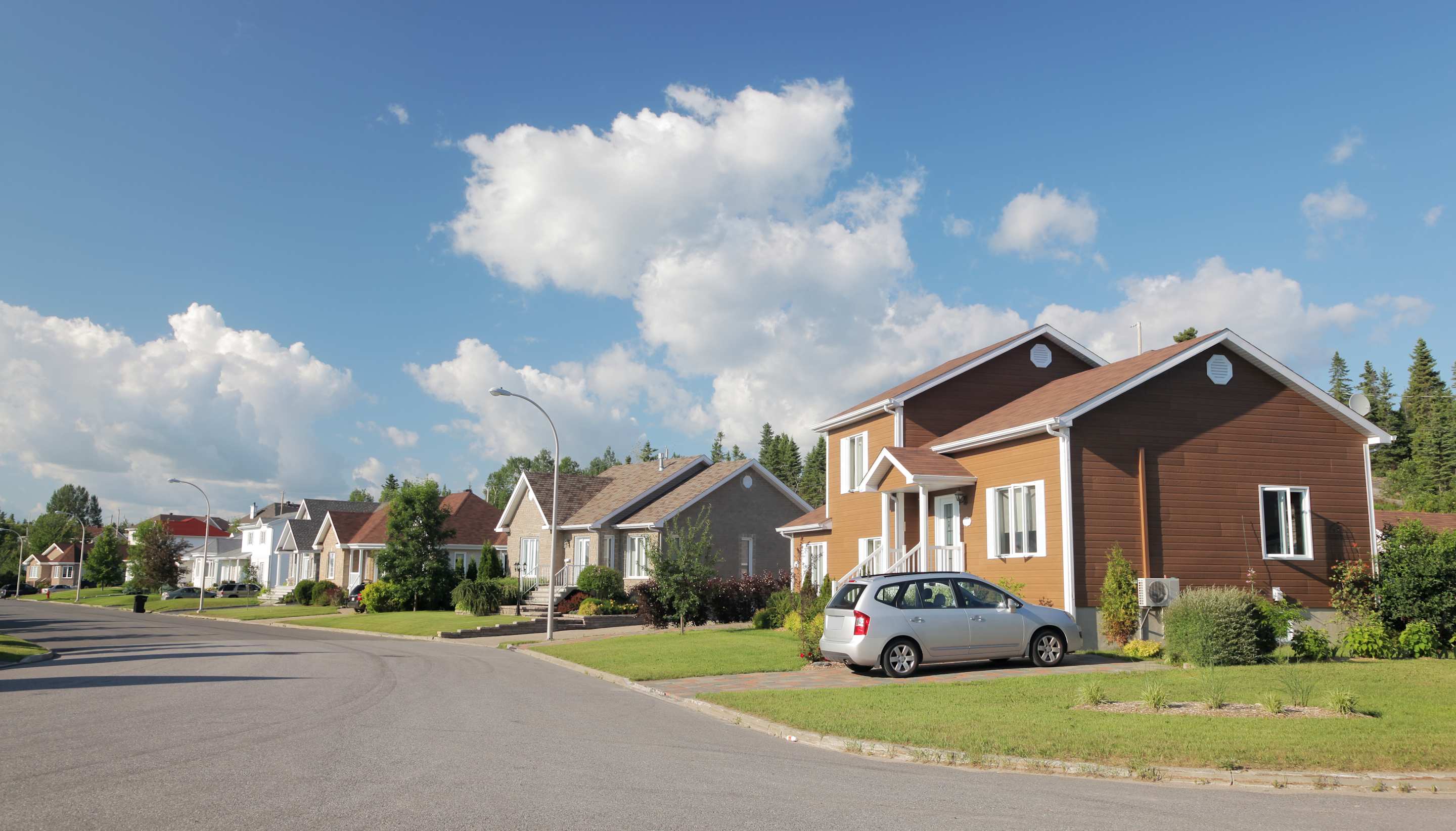 Some houses and a car parked in the driveway protected by AAA Home and Auto bundle insurance