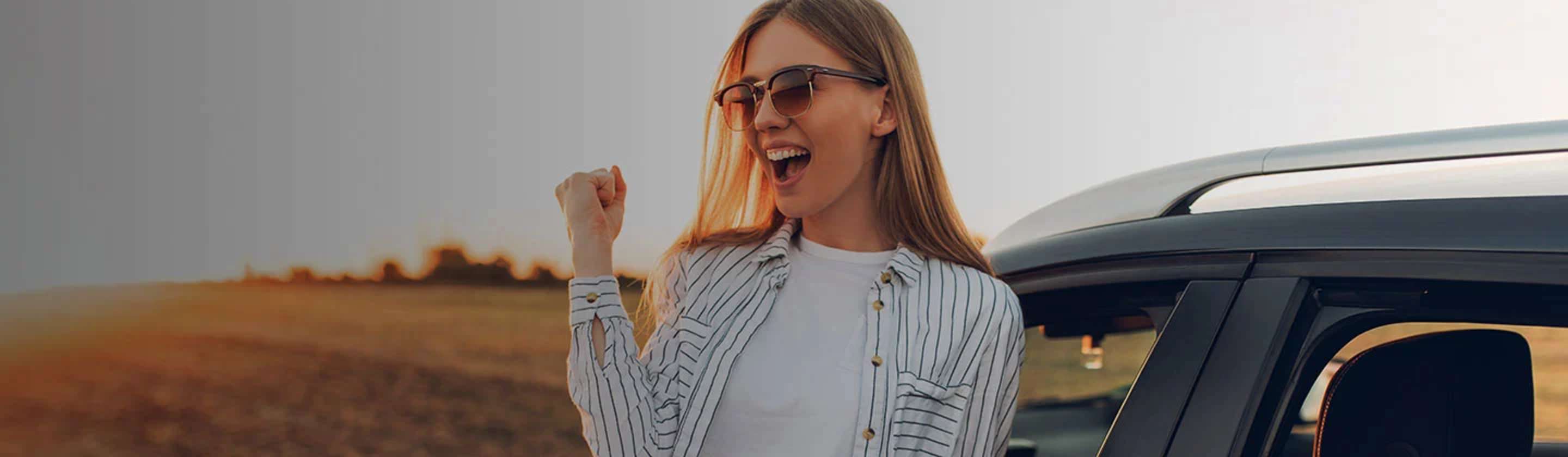 A woman celebrating near her car protected by aaa auto insurance