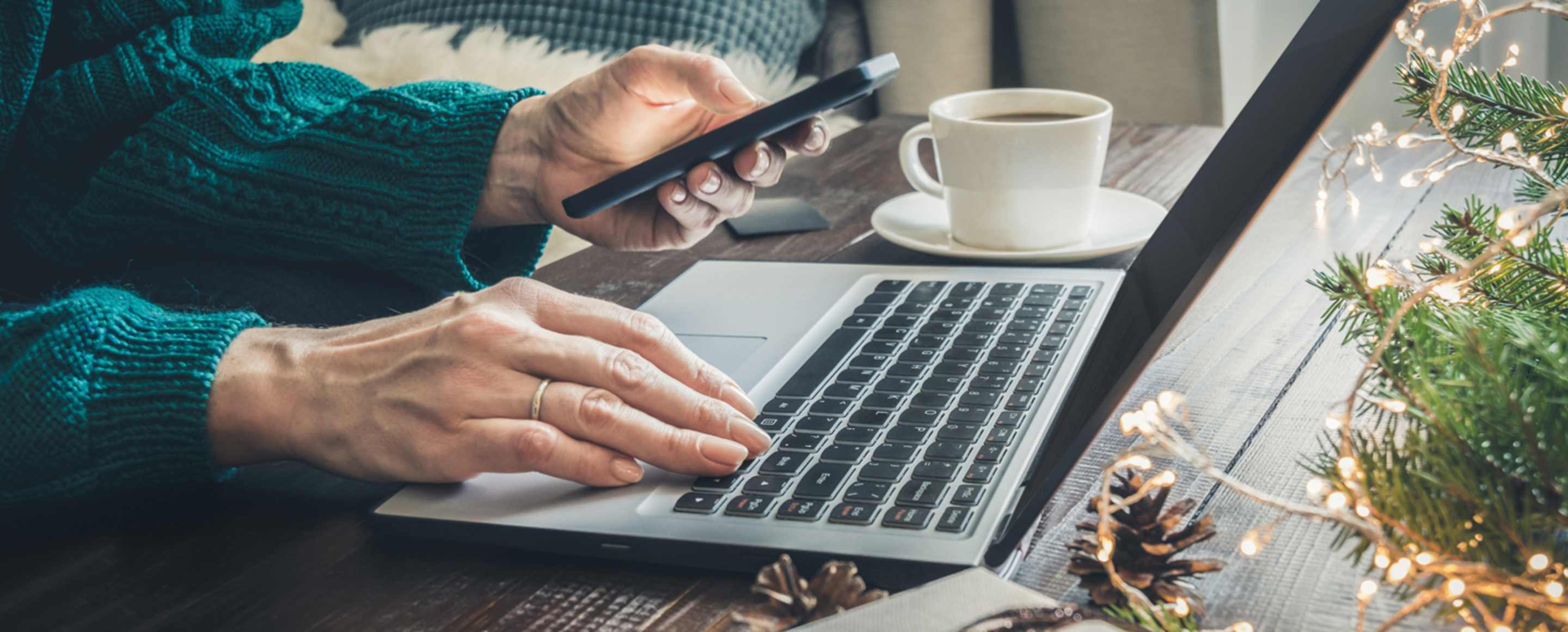 woman with phone searching on computer for black friday vacation deals