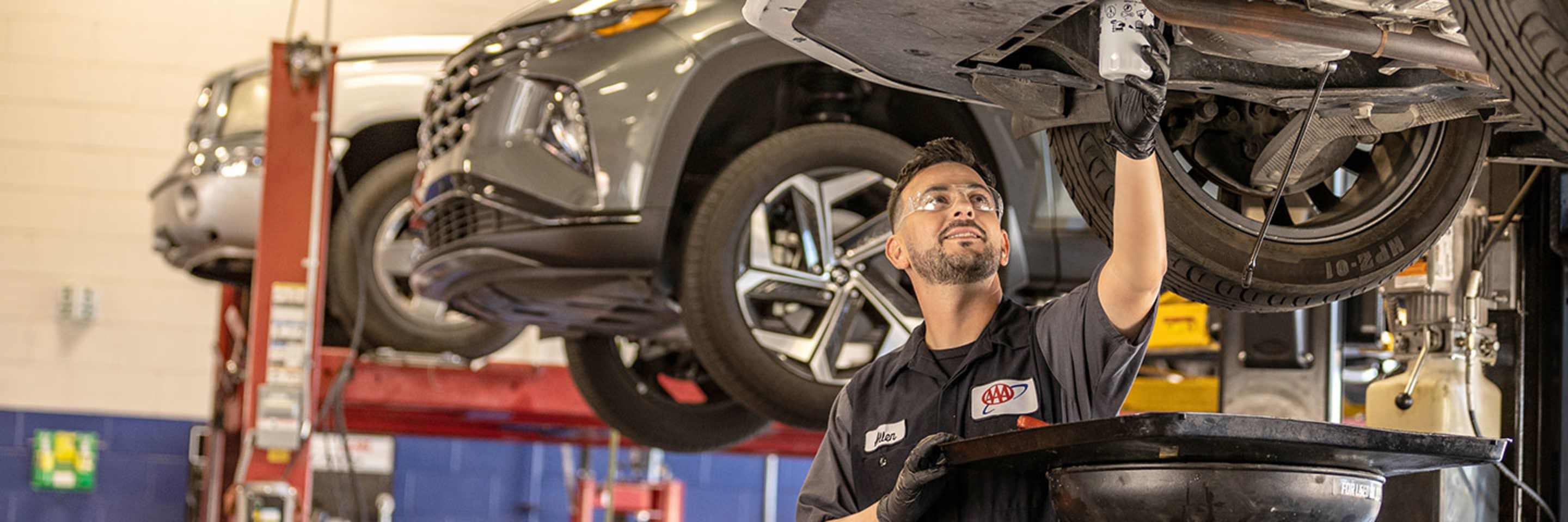 AAA mechanic working on a car with the hood open at an auto repair shop