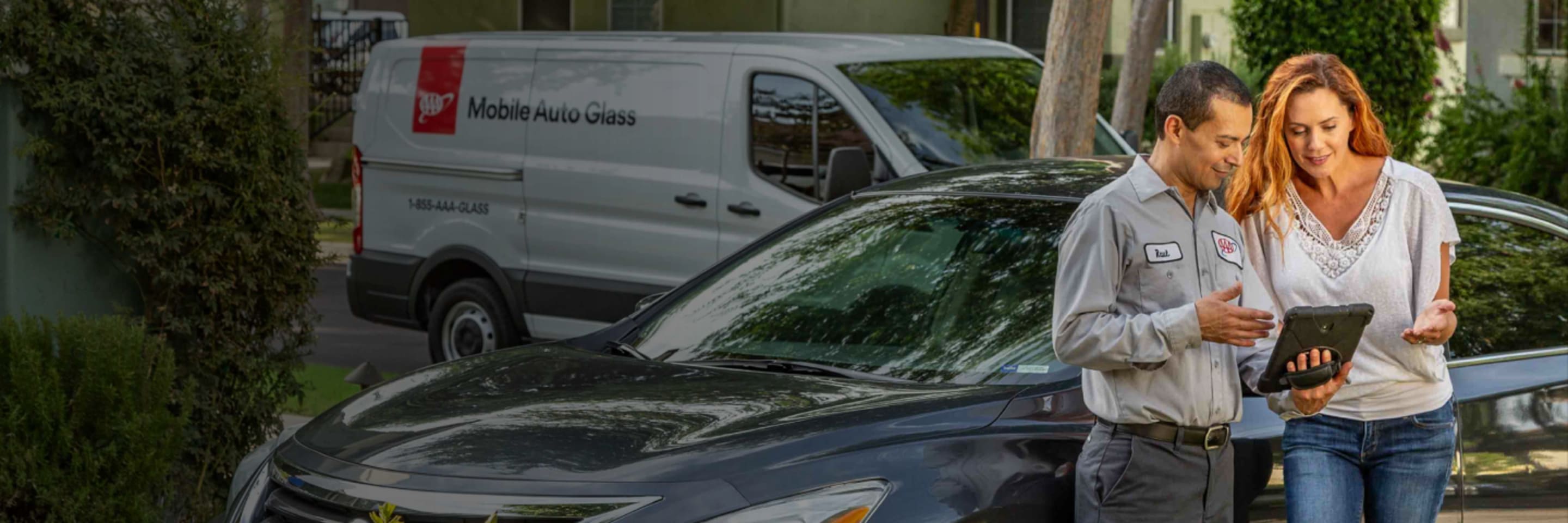 A mobile auto glass technician inspects a AAA Member's windshield for replacement