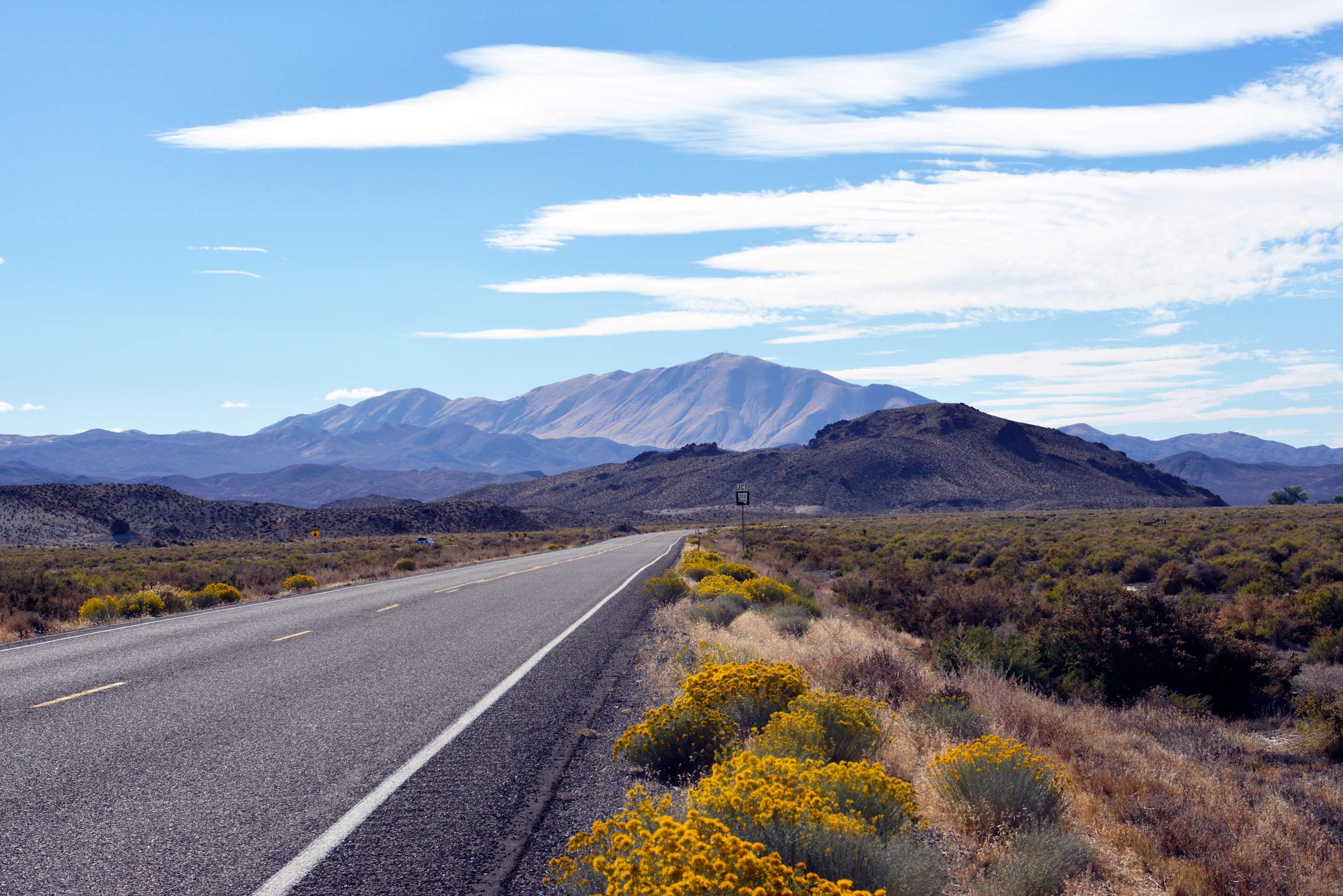 Empty Highway 50 stretches into the Nevada desert on a party cloudy day.