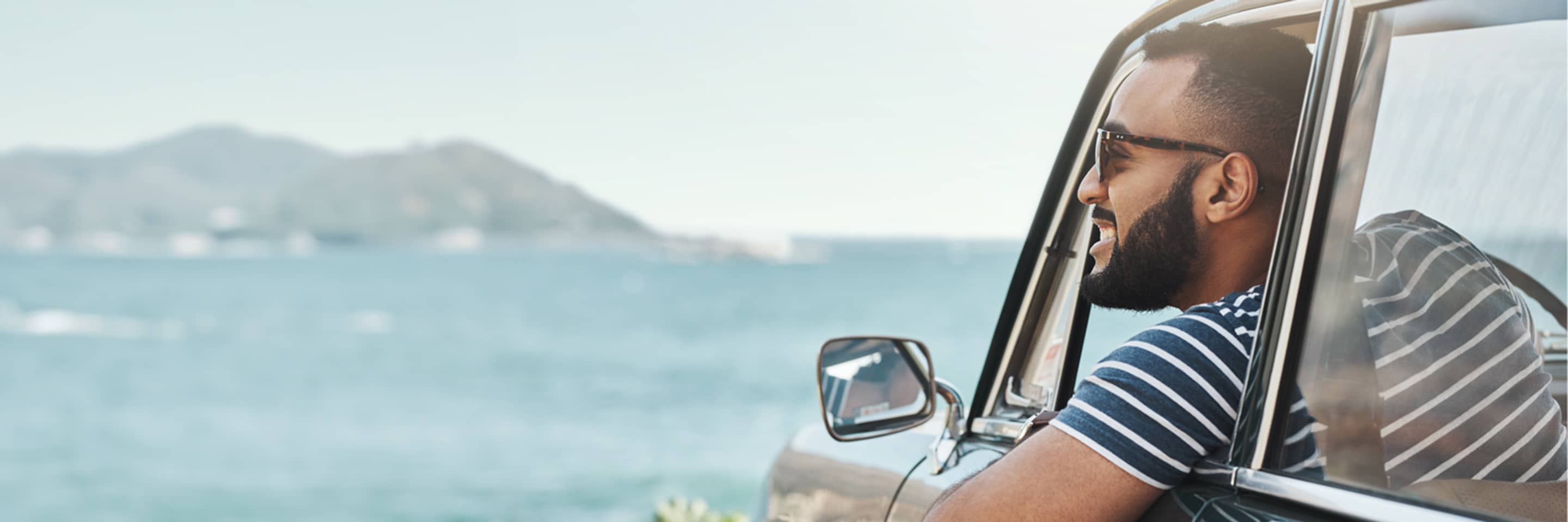 Man looking out of car window at ocean