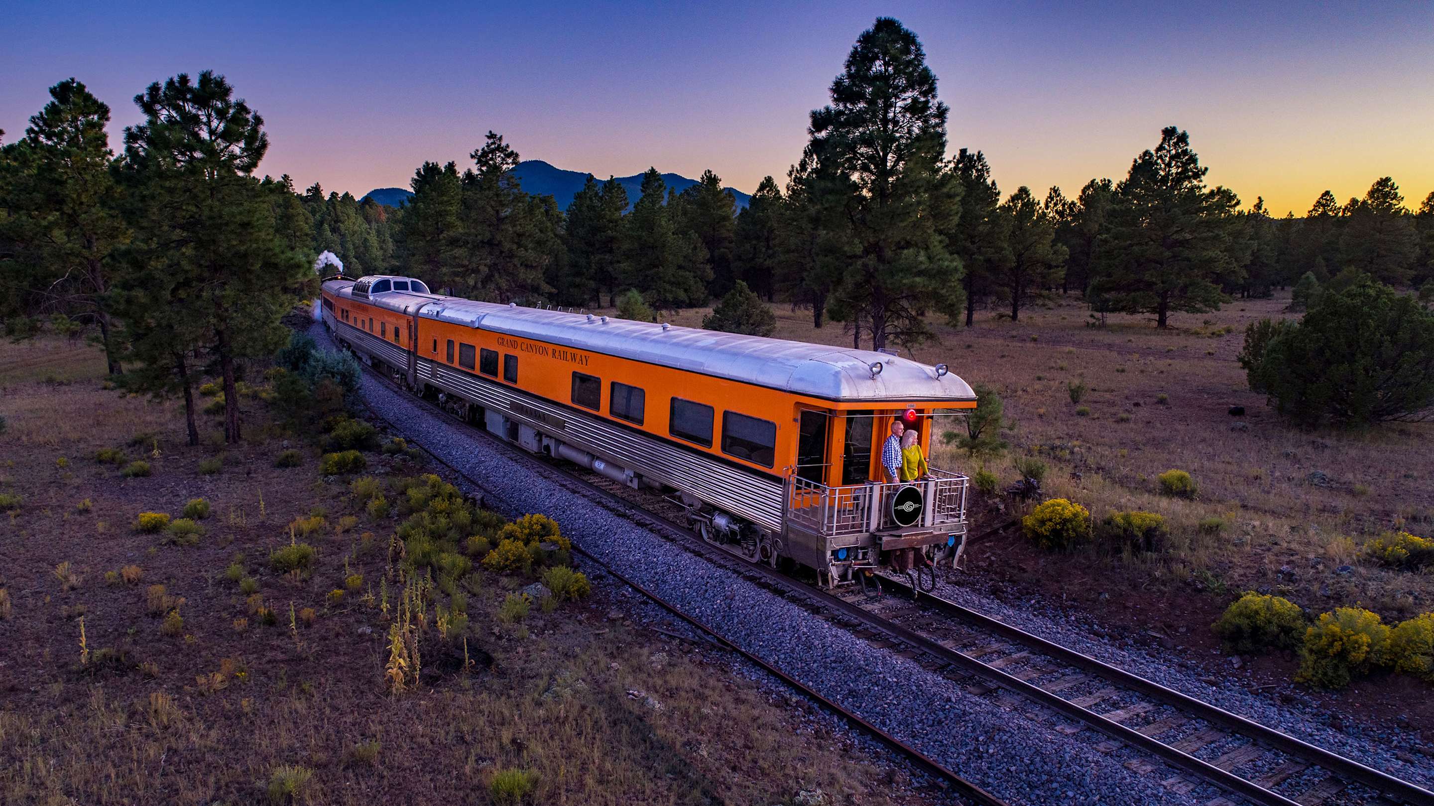 An orange Grand Canyon Railway car at dusk.