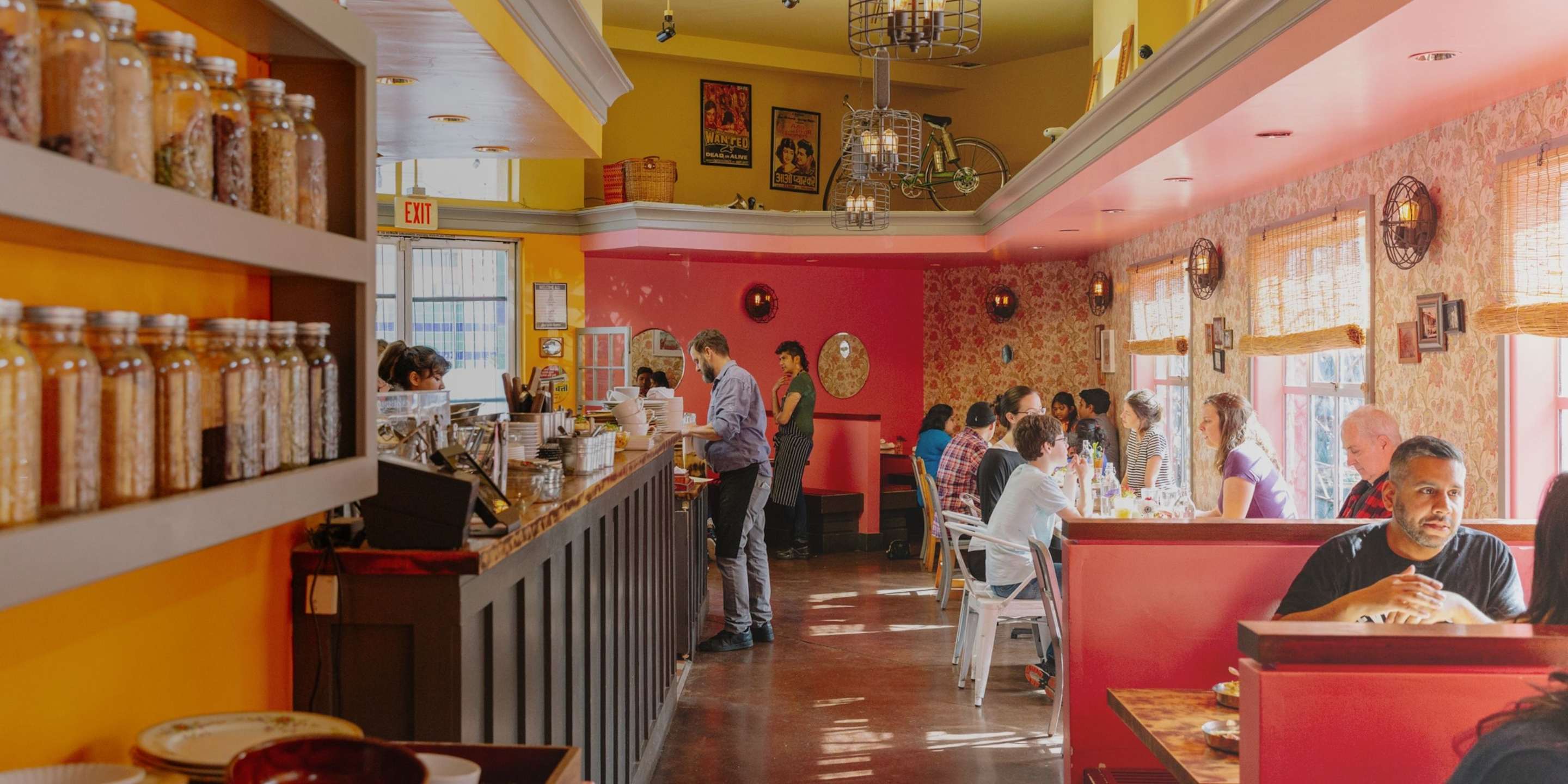 Spice jars and exotic prints line the colorful walls of a lively restaurant.