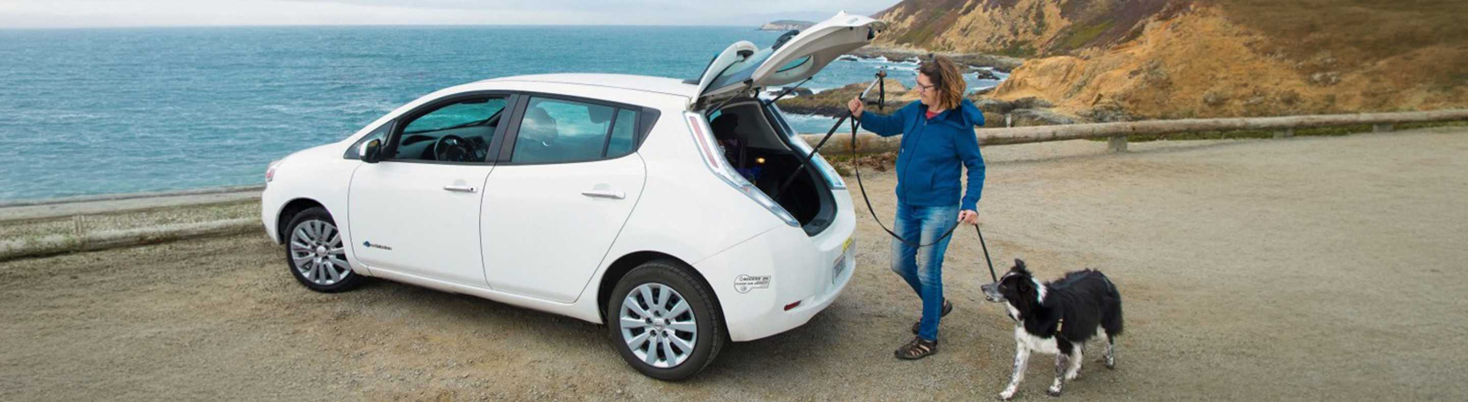 Father and daughter standing next to tesla