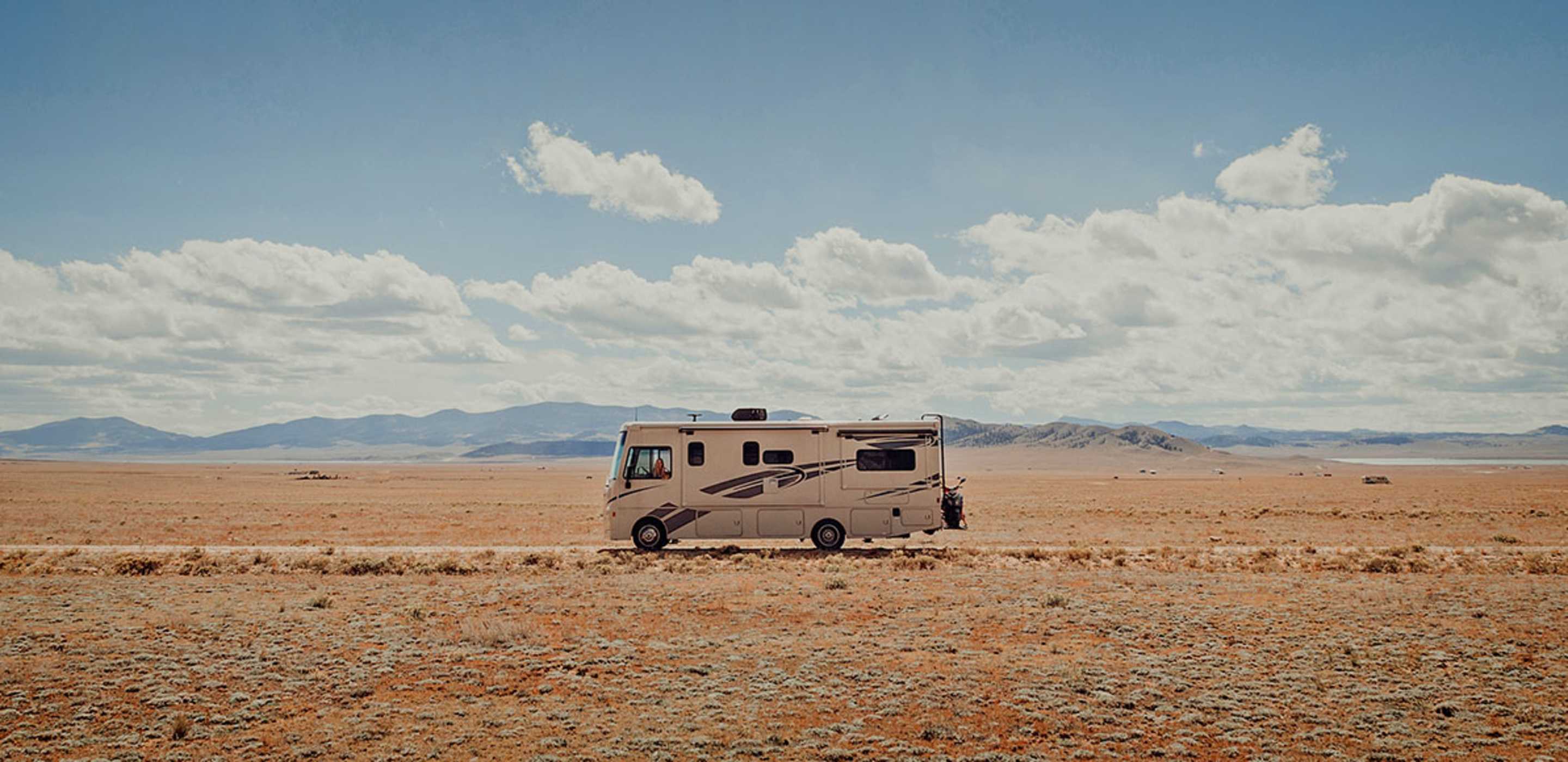 RV protected by AAA insurance driving down an open road in the desert.