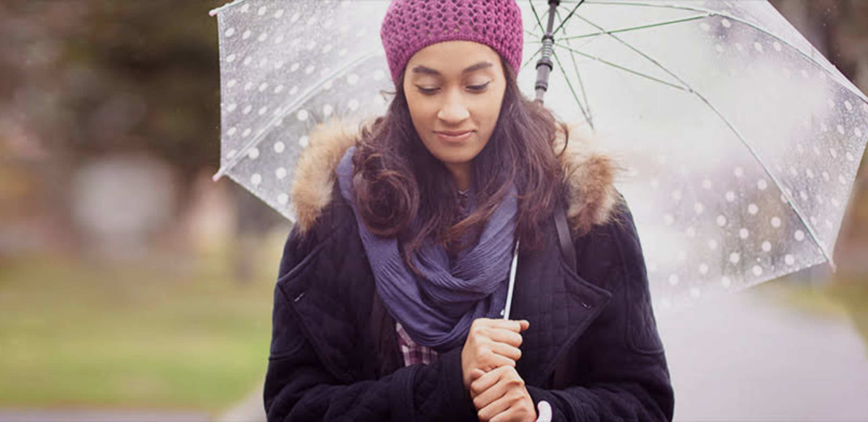 a woman with AAA insurance stands under an umbrella in the rain