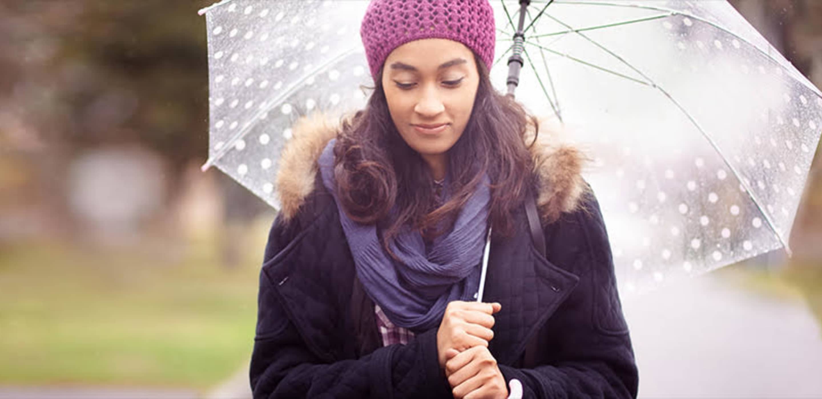 a woman with AAA insurance stands under an umbrella in the rain