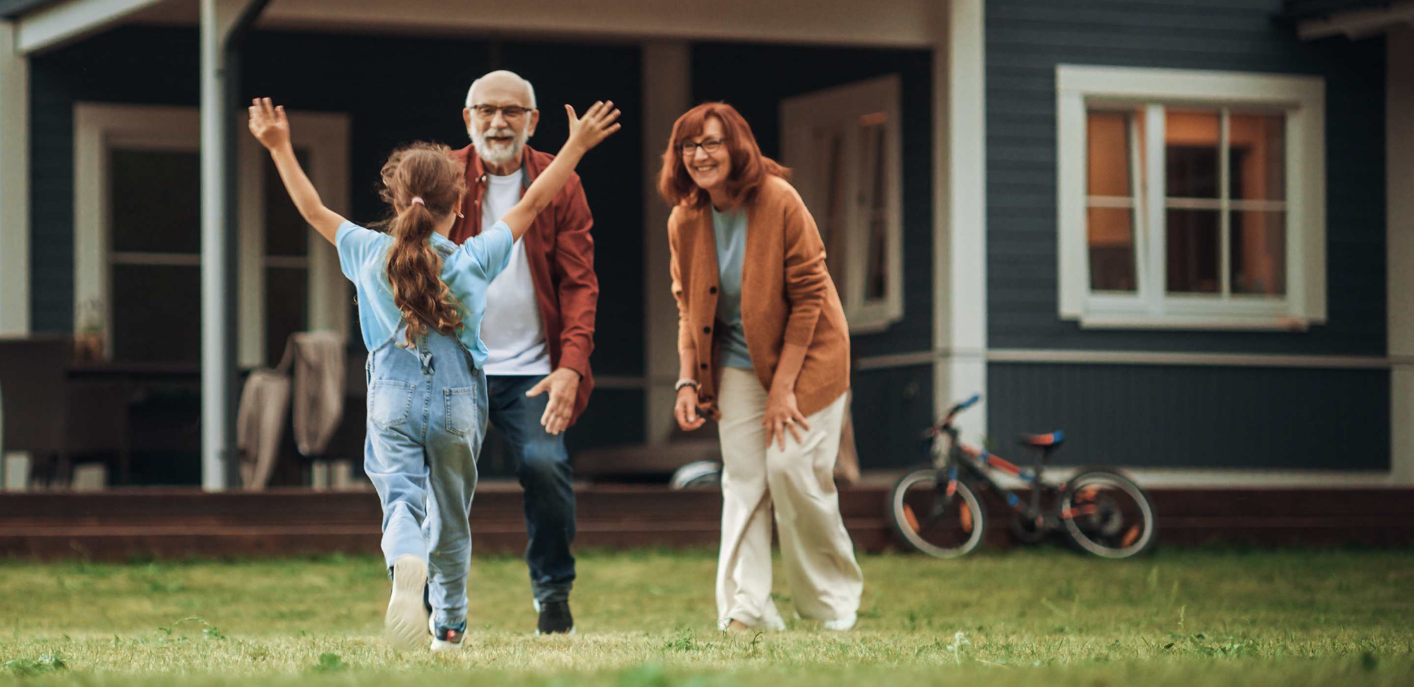 A child runs towards their grandparents who are AAA term life insurance policy holders