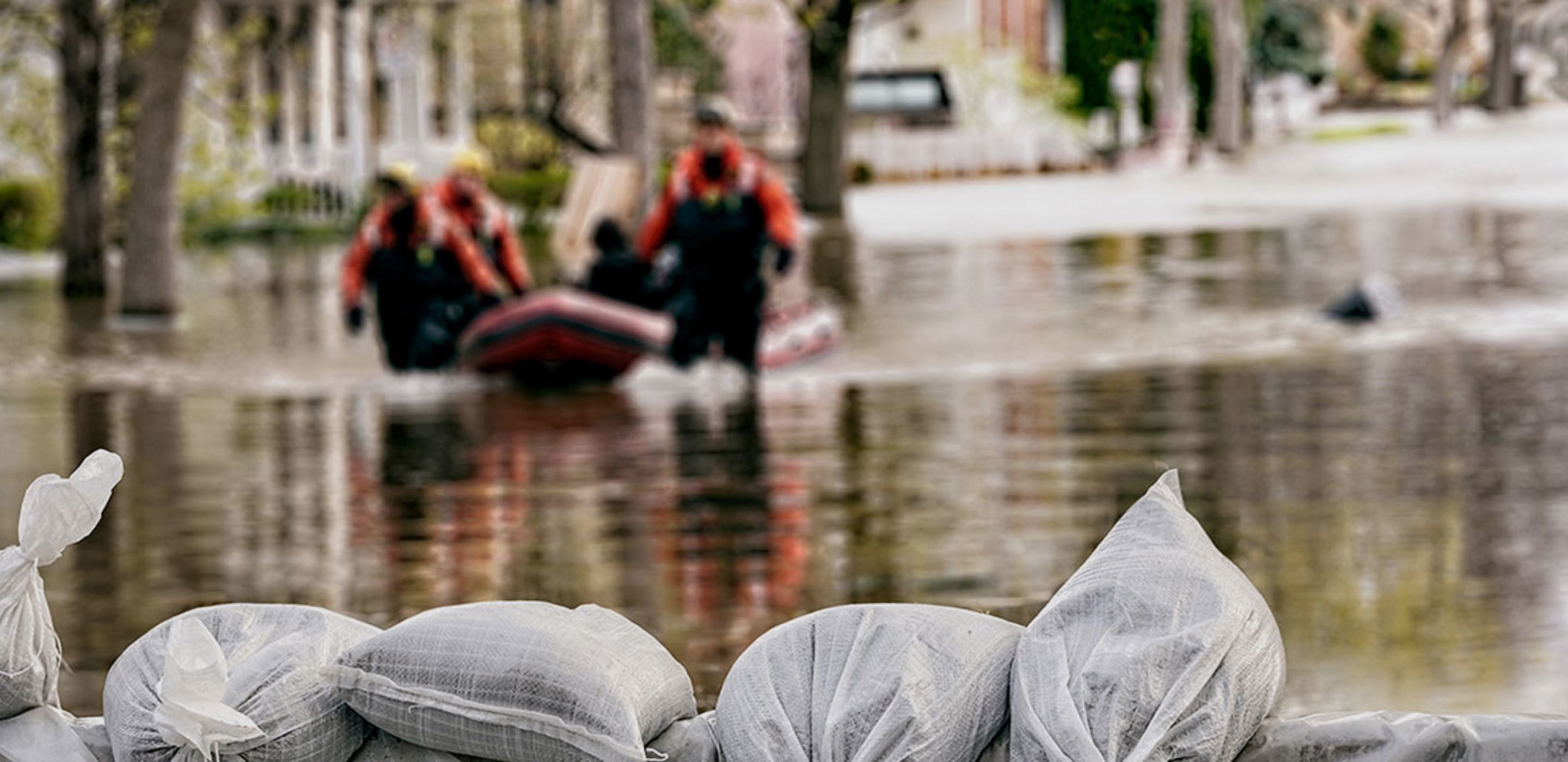 Workers pushing a boat in a flood zone surrounding a home covered by AAA Flood Insurance