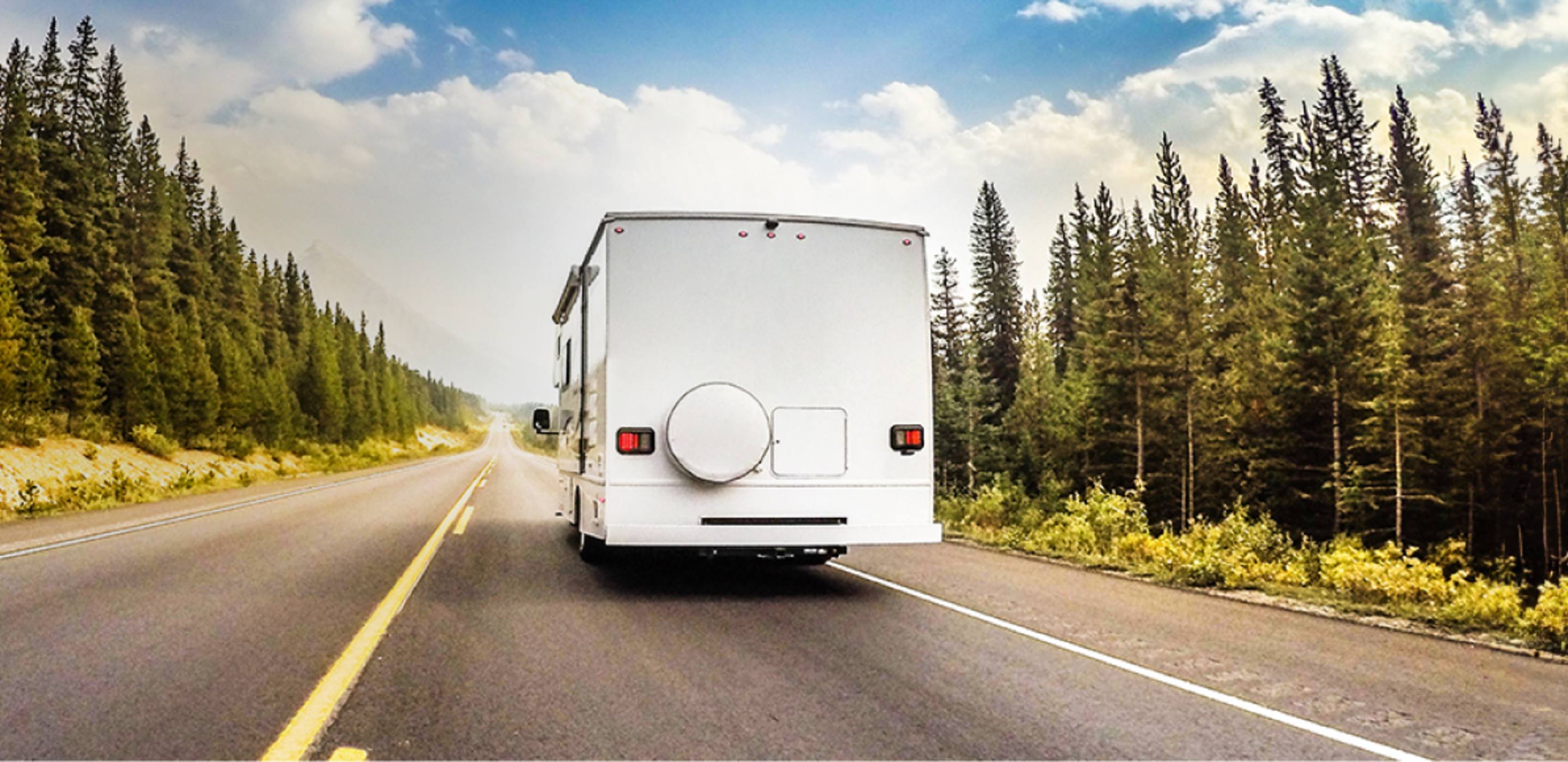 an insured RV drives down the road in a forested area