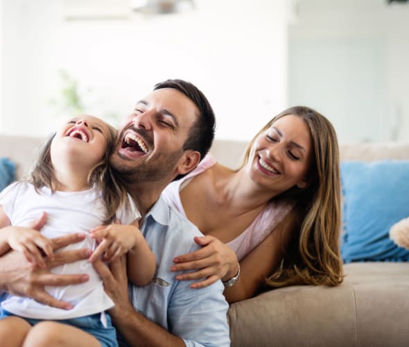 Family with AAA Life Insurance laughing on the couch.