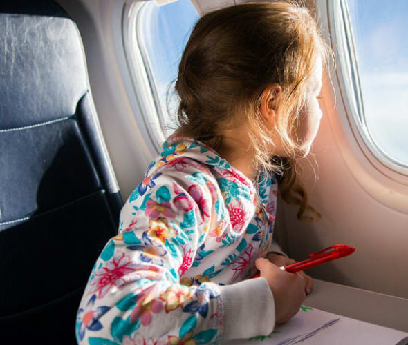 Kid flying in airplane looking out of the window