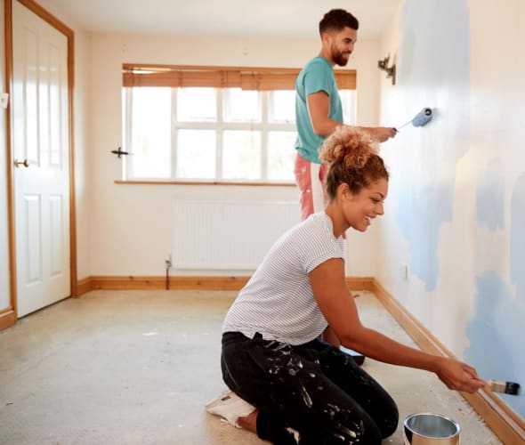 A couple paint a bedroom together.