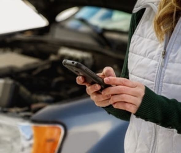 A woman uses the AAA app to request AAA Roadside assistance