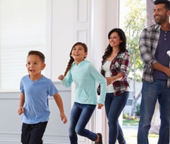 mother, father and two children walking through the front door of their home covered by aaa homeowners insurance