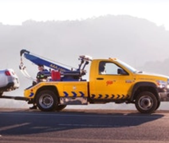 A AAA tow truck assists a car stranded on the side of the road.