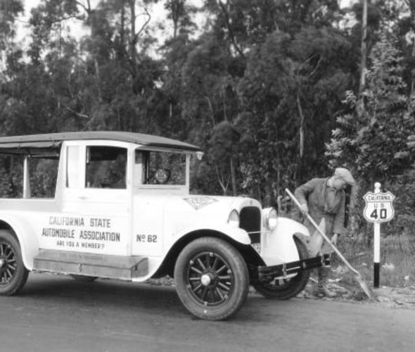 Old AAA truck with worker cleaning up along California highway 40