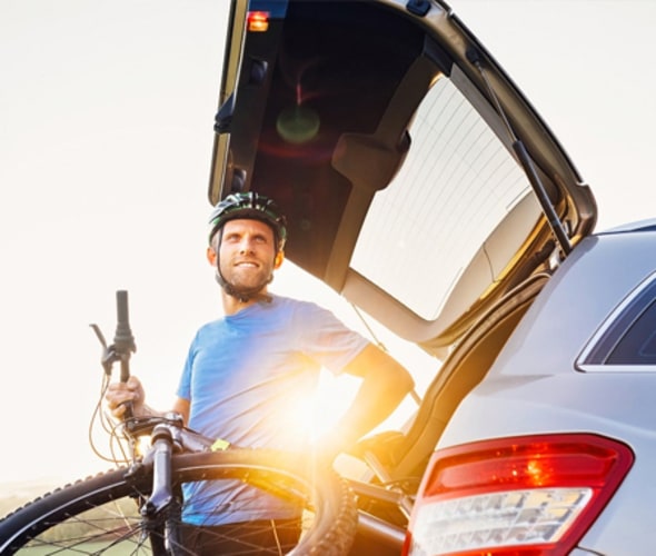 AAA Member unloading a mountain bike from his car at sunset