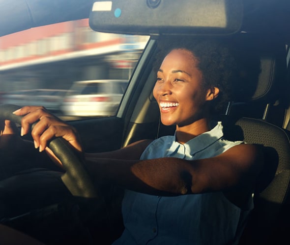 a smiling AAA member with AAA auto insurance drives her car 