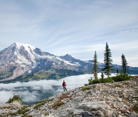 solo hiker takes in the panoramic view of Mount Rainier from Pinnacle Peak Trail in Washington