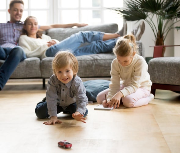 Little boy reaching for a toy car on the floor while his parents and sister watch