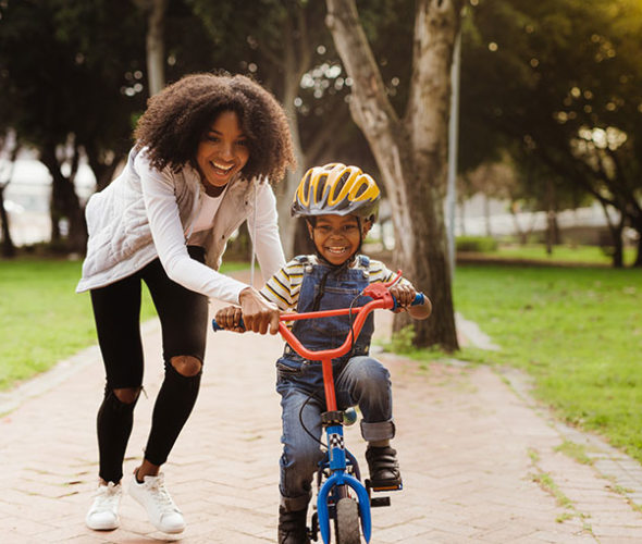 A AAA Life Insurance customer helps her son learn to ride his bike.
