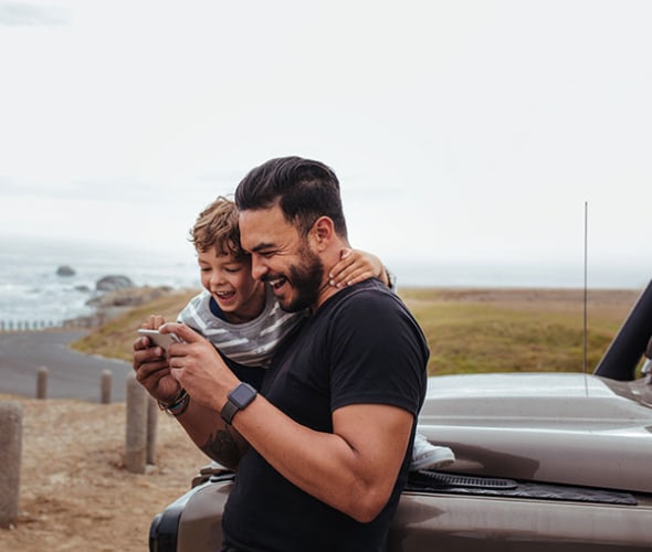 a AAA Member and his young son look at photos on a coastal road trip 