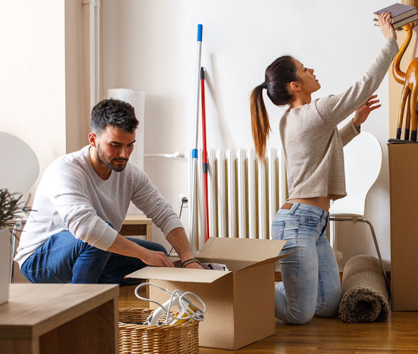 A man and woman unpack moving boxes in their new apartment with aaa renters insurance