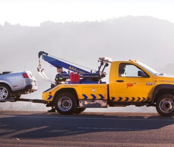 A AAA tow truck assists a car stranded on the side of the road.